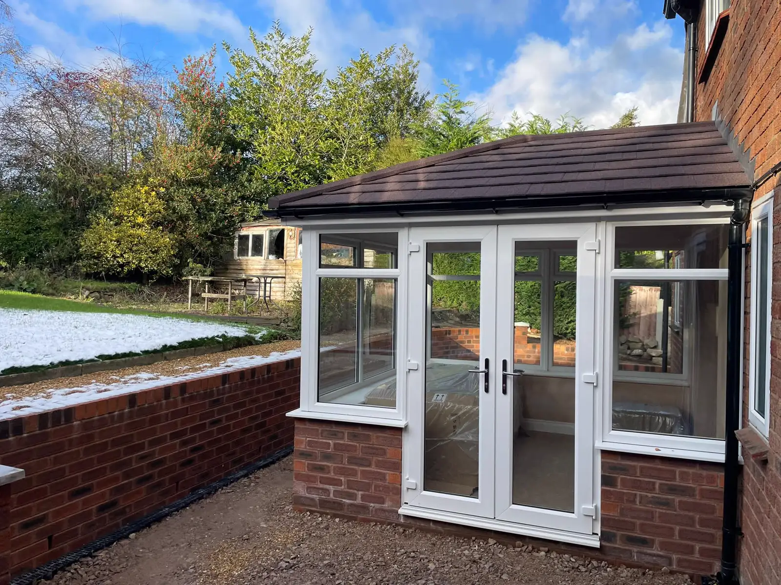 White-framed conservatory with French doors and a tiled roof